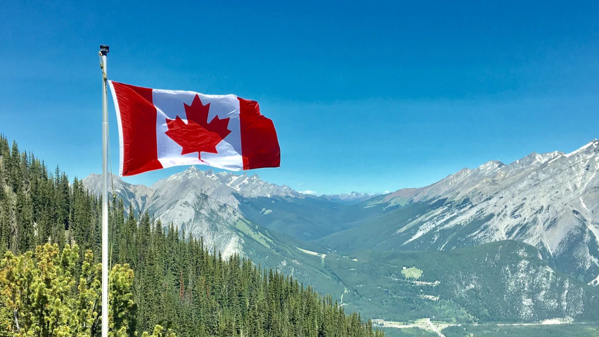 An image of a Canadian Flag in front of a mountain range